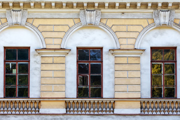 The architectural element of the wall of an old estate with three vertical arched windows and a balustrade