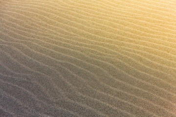 Fototapeta na wymiar The abstract wave line textures on a Pacific beach illuminated by the Sun and an empty quarter