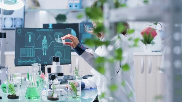 Senior biochemist looking at some green bio samples in modern laboratory