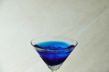 ชื่อ	 Fresh purple butterfly pea or blue pea flower and juice in glass on table blue and white background with green blur light space background design, photo montage or advertising