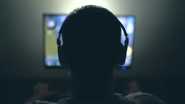 Gamer with Headphones in Dark Room playing Video Game at Night