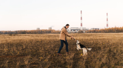 Obraz premium A man with a mongrel dog walking on autumn meadow