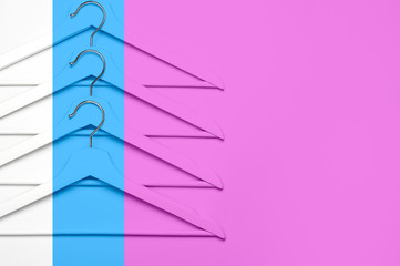 Creative fashion concept. Flat lay top view colored wooden hangers on pink blue background minimalism style pop-art. Sale discount store shopping concept, design empty hanger. Beauty feminine blog