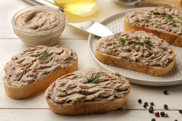 Fresh homemade chicken liver pate with herbs for bread on a white wooden table. A sandwich.