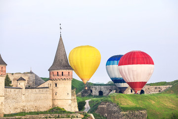 Fototapeta na wymiar View of old fortress and hot air balloons in countryside