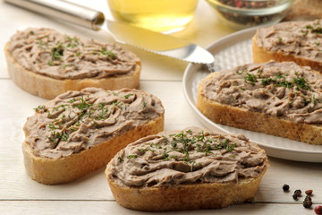 Fresh homemade chicken liver pate with herbs for bread on a white wooden table. A sandwich. close-up