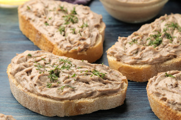 Fresh homemade chicken liver pate with herbs on bread on a blue wooden table. A sandwich. close-up
