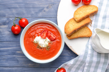 Bowl of tasty tomato cream soup on wooden table