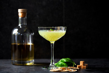 Bottle of strong alcoholic drink and a glass of tasty Basil Daiquiri cocktail