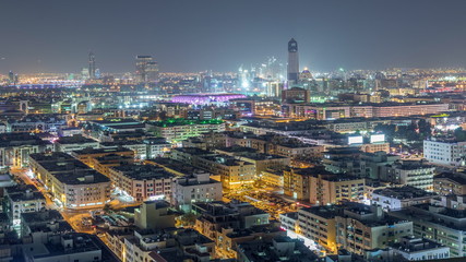Fototapeta premium Aerial view of neighbourhood Deira with typical buildings night timelapse, Dubai, United Arab Emirates