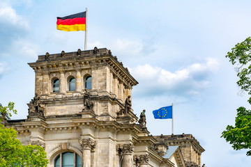 Naklejka premium German and EU flags raising over Reichstag building (Bundestag - parliament of Germany) in Berlin