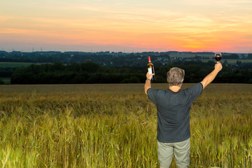Man celebrates outdoors with wine in the country side during twilight