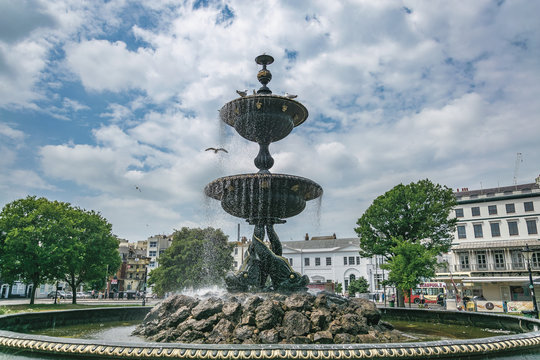 Victoria fountain in Old Steine Gardens, Brighton, England, during the day surrounded by seagulls.