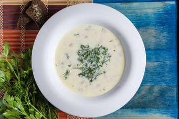 soup with vegetables and cheese in a white plate blue wooden background