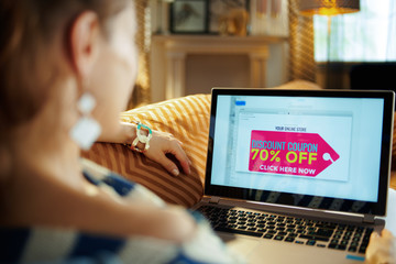 woman reading e-commerce email with discount coupon on laptop