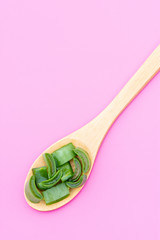 Medicinal plant aloe vera on a wooden spoon on a pink background