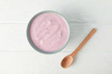 Fototapeta na wymiar Fruit yogurt in bowl and spoon on white wooden background