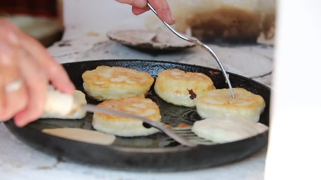 A person making pancakes in the old pan using large amount of oil