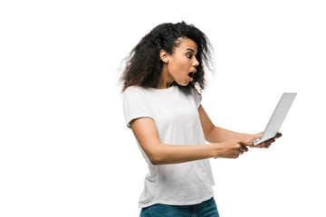 shocked african american girl looking at laptop isolated on white