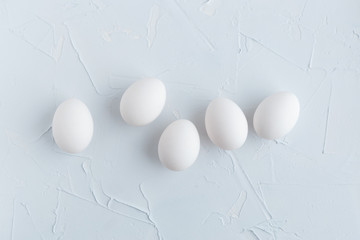 White eggs on blue texture background. Top view.