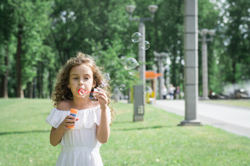 Happy little girl playing soap bubbles in garden