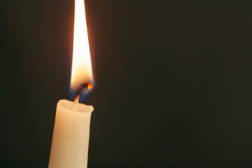 A single burning candle isolated with black background