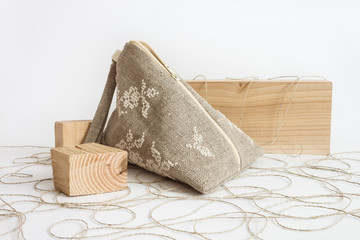 Linen cosmetic bag with embroidered  white ornament on a light background