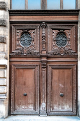 Old wooden door. Antique double door gate with of aged ornate carving fretwork wooden panels and door windows of building in Paris France. Vintage doorway of baroque architecture of Louvre.