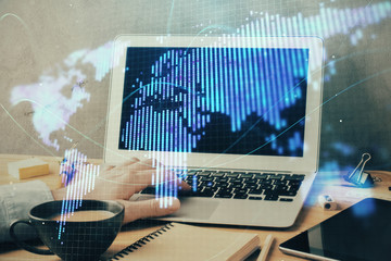 Double exposure of businessman working on laptop on background. International business hologram in front. Concept of success.