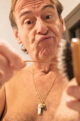 Homme regardant les cheveux qui sont tombés sur sa brosse à cheveux en faisant la grimace