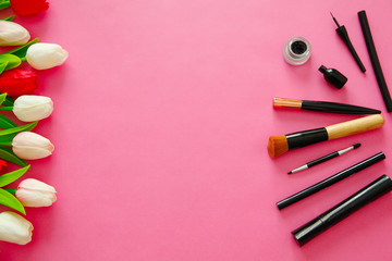 Cosmetics brushes and tulips on the bright pink background. Copyspace concept. Glamour concept. 