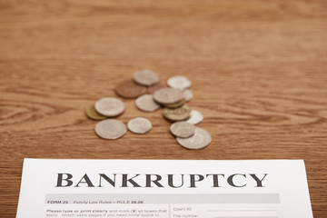 bankruptcy form and metal coins on brown wooden table