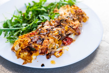 Omelete with arugula on white plate