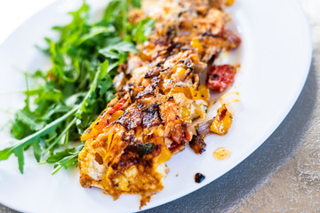 Omelete with arugula on white plate