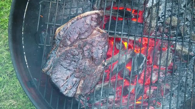 Succulent steak being grilled on a barbecue. Slow motion