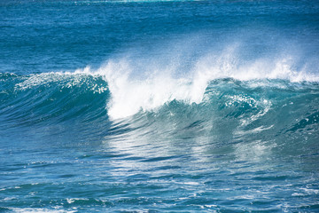 Fototapeta na wymiar A wave breaking in the blue Atlantic ocean.