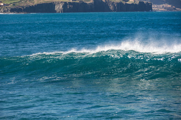 Wave breaking in the blue ocean near the city.