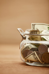close up view of glass jar with dollar banknotes and coins