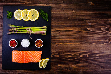 Fresh raw salmon fish served on black stone on wooden table