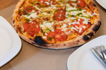 Pizza Margherita with mozzarella, with tomatoes, and tomato sauce on a plate in restaurant