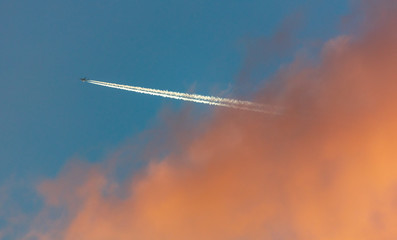 Trail from the plane in the sky at sunset