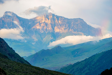 Scenic view of foggy mountains. Sunlit rocks and clouds