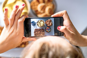 Girl eats fast food and take a pictures of it on smartphone at work. Unhealthy food: chips,...