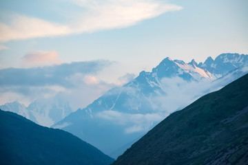 Obraz premium Scenic view of foggy mountains. Sunlit rocks and clouds