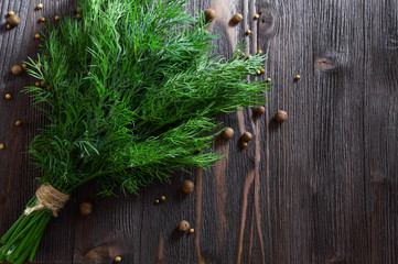 Bunch of fresh dill and spices on dark wooden background. Flat-lay, top view.