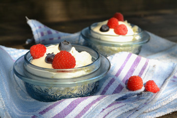Cottage cheese in glass bowl with raspberries and blueberries on a blue napkin. Healthy Breakfast.