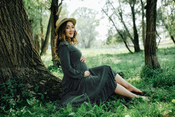 Obraz premium Young pregnant woman relaxing in park outdoors