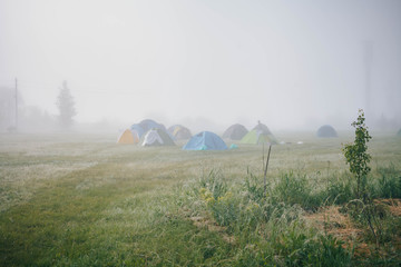 tent camp in the early foggy morning on a clearing near the forest