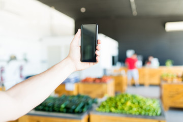 Hand Using Smartphone In Blur Supermarket
