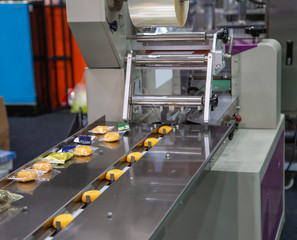 Cake package on cake flow wrapping packaging machine in bakery production line. Food industry